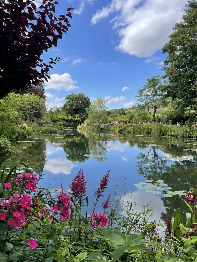 空と雲を映すジヴェルニーの睡蓮の池と、岸辺に咲く花々